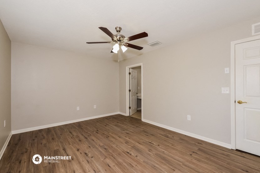 the spacious living room with wood flooring and a ceiling fan