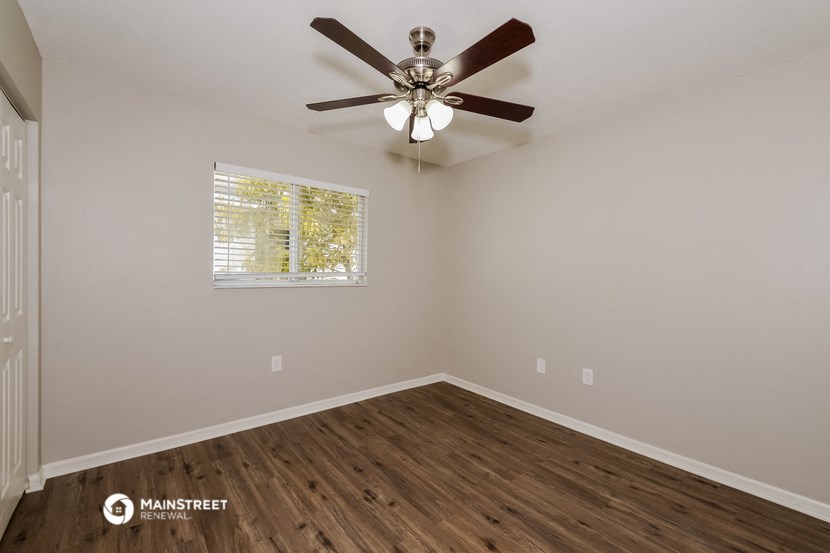 the spacious living room with ceiling fan and wood flooring
