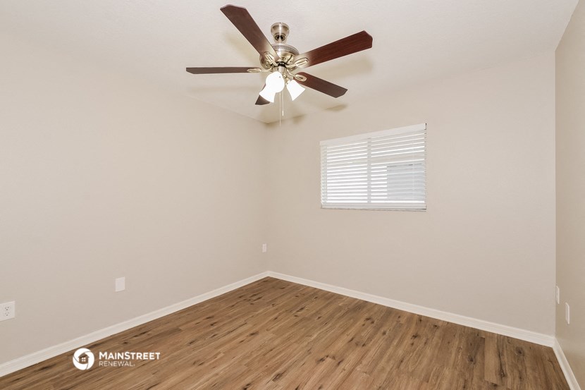 the bedroom has a ceiling fan and hardwood floors