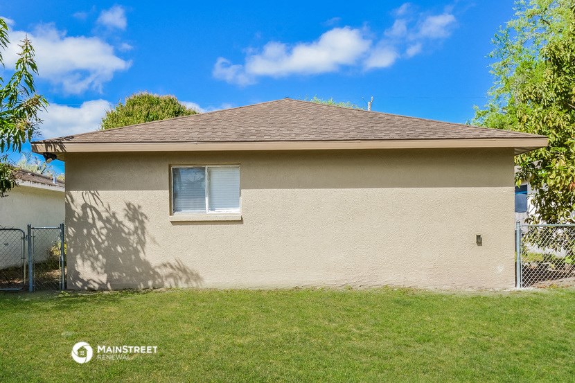 the front of a house with a yard and a fence