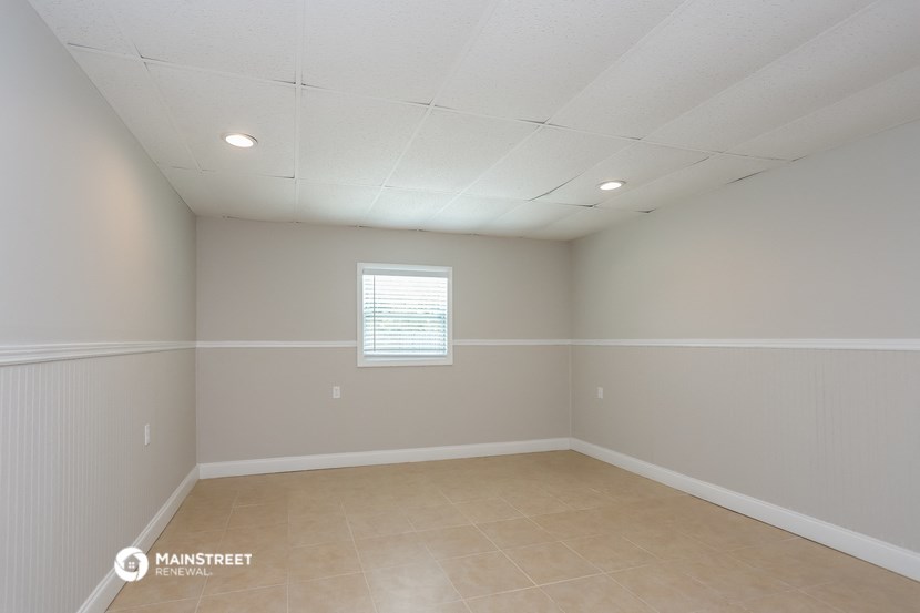 the interior of an empty room with beige tile and white walls and a window