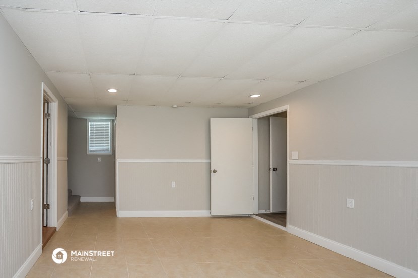 an empty living room with white walls and a tile floor