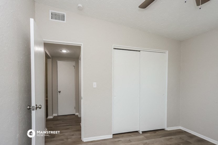 the living room of an apartment with white walls and a door to the closet