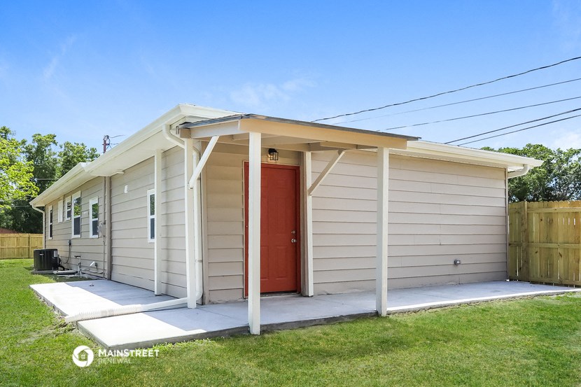 a small white house with a red door and a porch