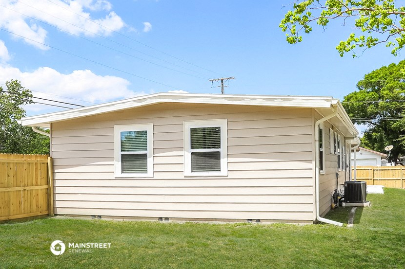 the exterior of a house with white siding and a wooden fence