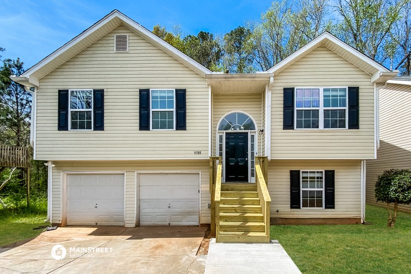 a tan house with black shutters and a black door