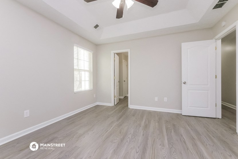 the living room of a new home with white walls and a ceiling fan