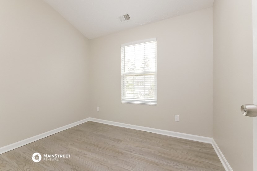 an empty room with wood floors and a window