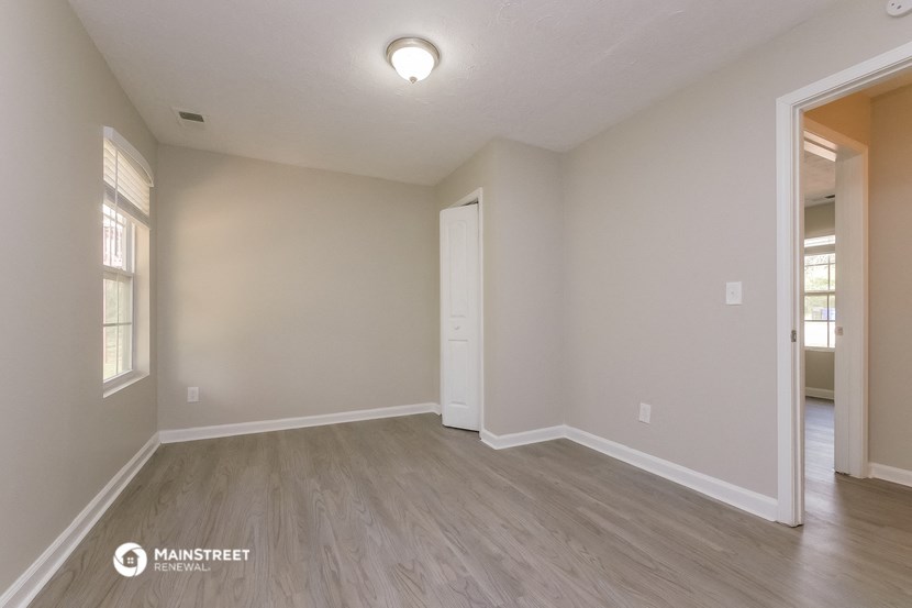 the spacious living room with wood flooring and white walls