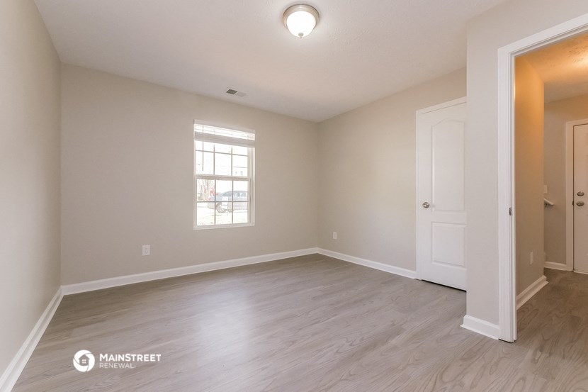 the spacious living room with hardwood flooring and a window