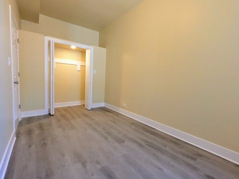 an empty living room with wooden floors and a door to a hallway