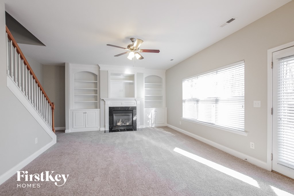 an empty living room with a fireplace and a ceiling fan