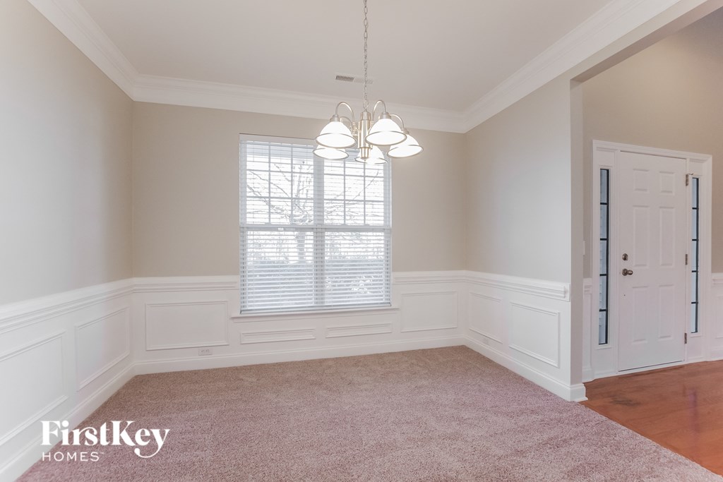 an empty dining room with white wainscoting and a window