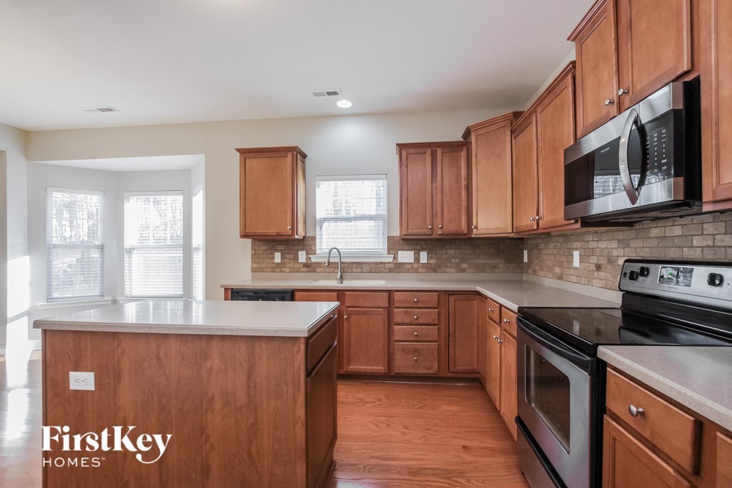 a kitchen with wood cabinets and black appliances and white counter tops
