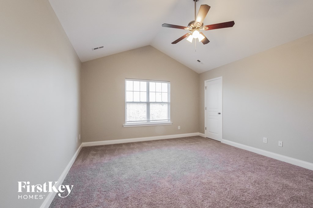 an empty living room with a ceiling fan and a window