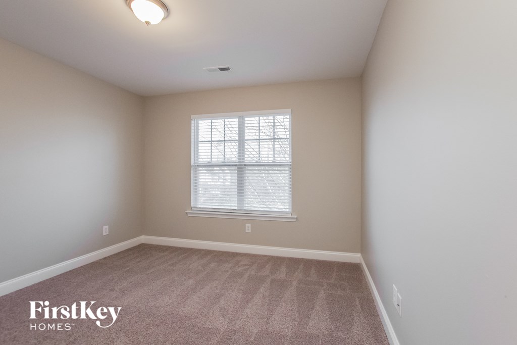 a bedroom with a large window and a carpeted floor