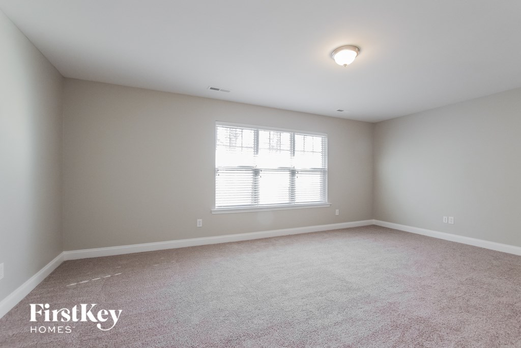 a bedroom with white carpet and a window
