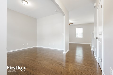 the living room and dining room with hardwood floors and white walls