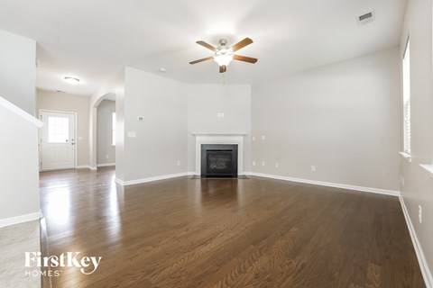 an empty living room with a ceiling fan and a fireplace
