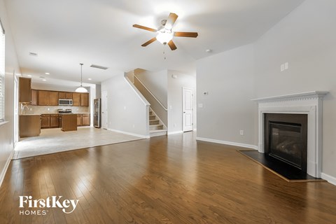 an empty living room with a fireplace and a ceiling fan