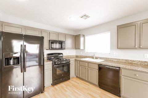 A kitchen with a stainless steel refrigerator and wooden floors.