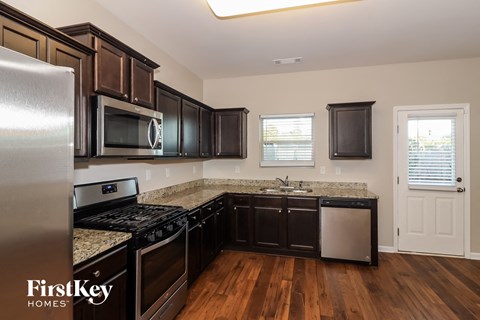 an updated kitchen with black cabinets and granite counter tops and stainless steel appliances