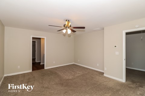 a living room with carpet and a ceiling fan