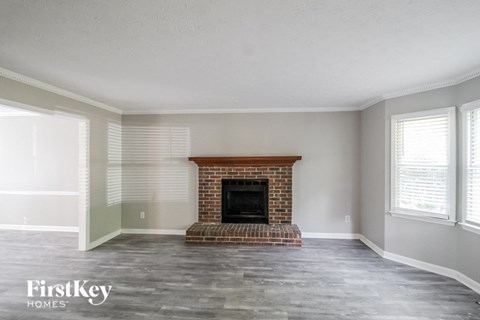 an empty living room with a brick fireplace