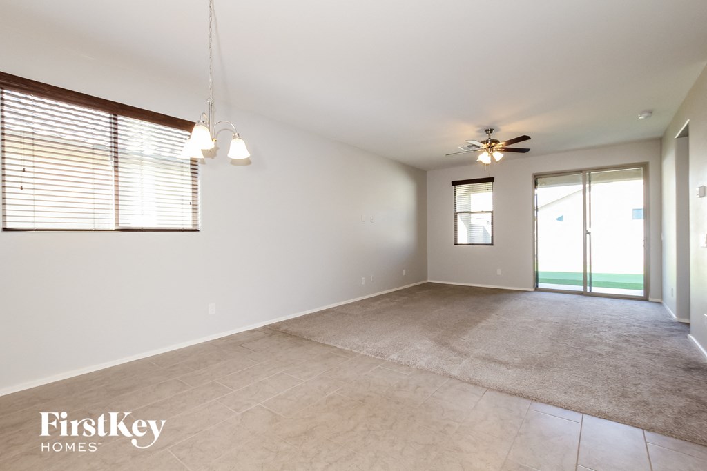 A spacious room with a carpeted floor and a ceiling fan.