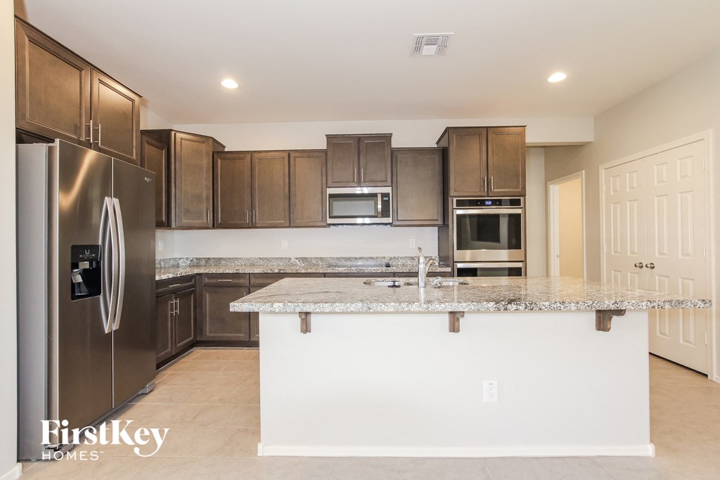 A kitchen with a granite countertop and stainless steel appliances.