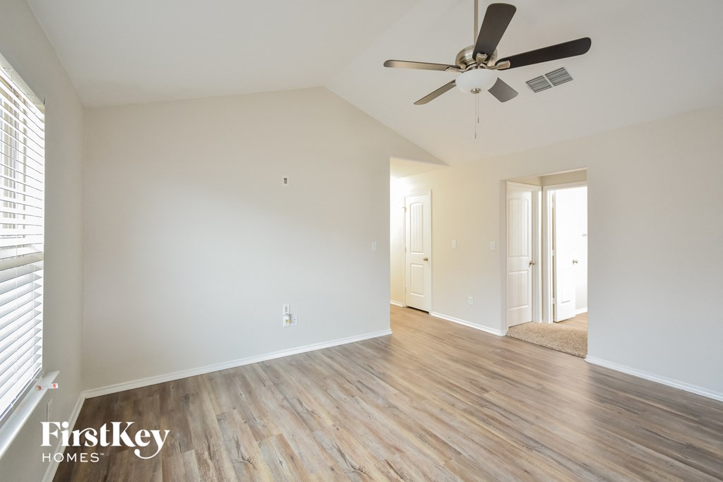 a living room with white walls and a ceiling fan
