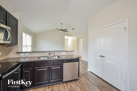 a kitchen with black cabinets and stainless steel appliances and a white door