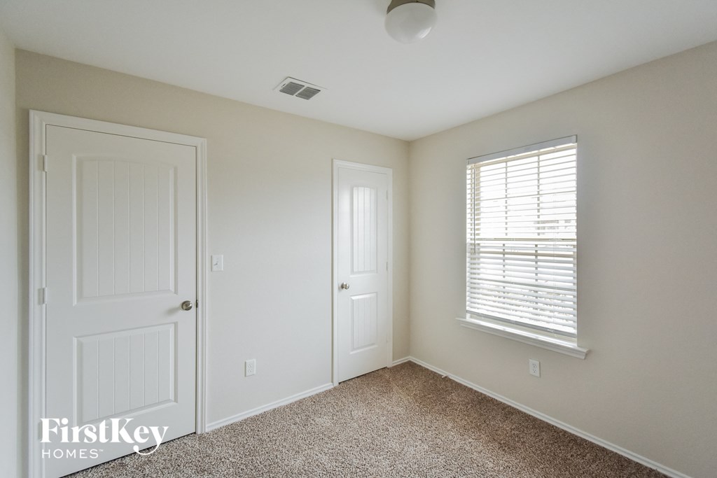 a bedroom with a closet and a window and a white door
