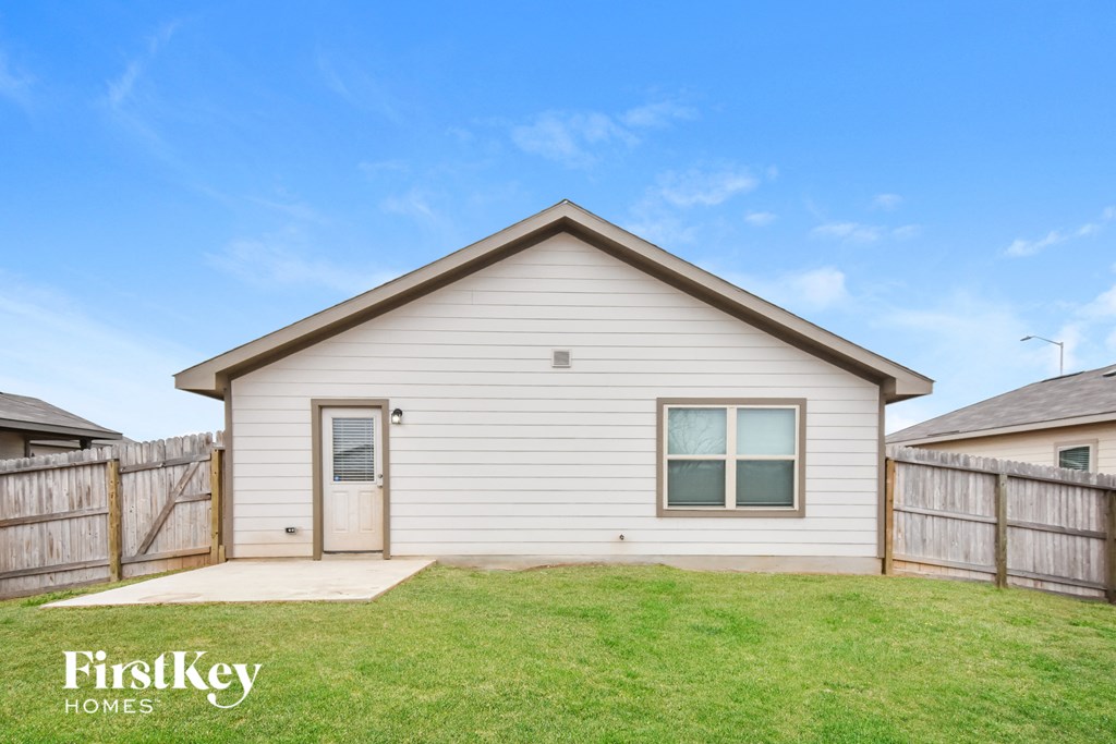 the outside of a small white house with a yard and a fence