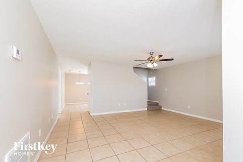 a spacious living room with tile flooring and a ceiling fan