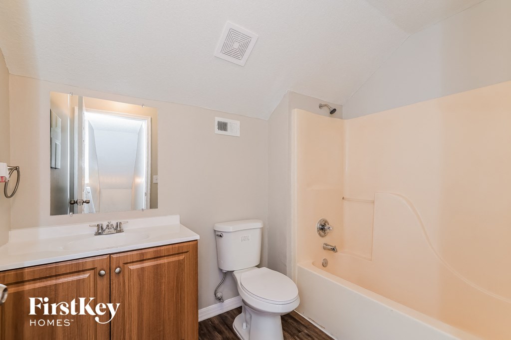 a bathroom with a toilet sink and tub and a mirror