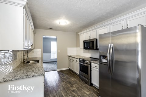 A kitchen with a refrigerator, microwave, and oven.