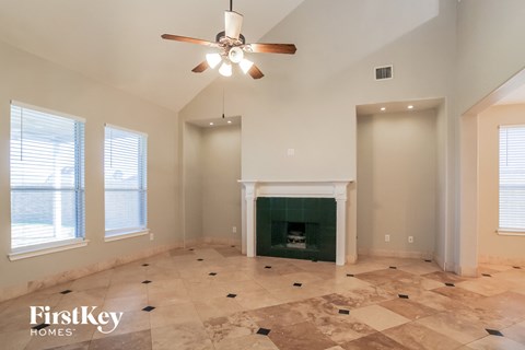 A spacious living room with a fireplace and a ceiling fan.