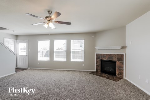 A spacious living room with a fireplace and a ceiling fan.
