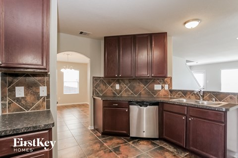 A kitchen with brown cabinets and a marble counter top.