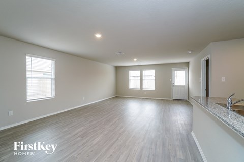 A spacious room with wooden flooring and a kitchen area with a sink.