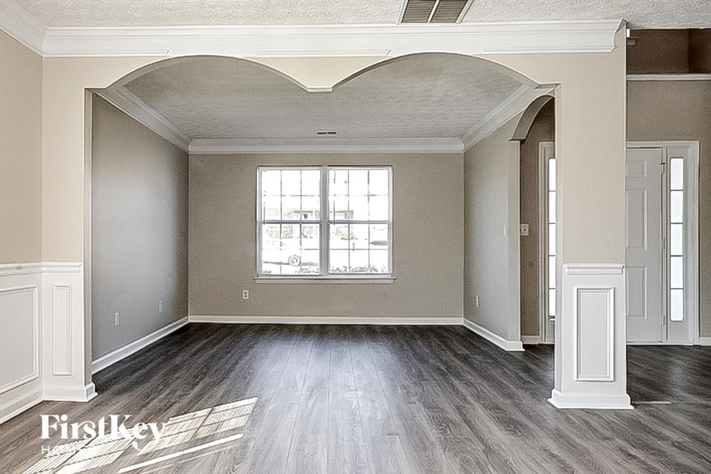 an empty living room with wood floors and a window