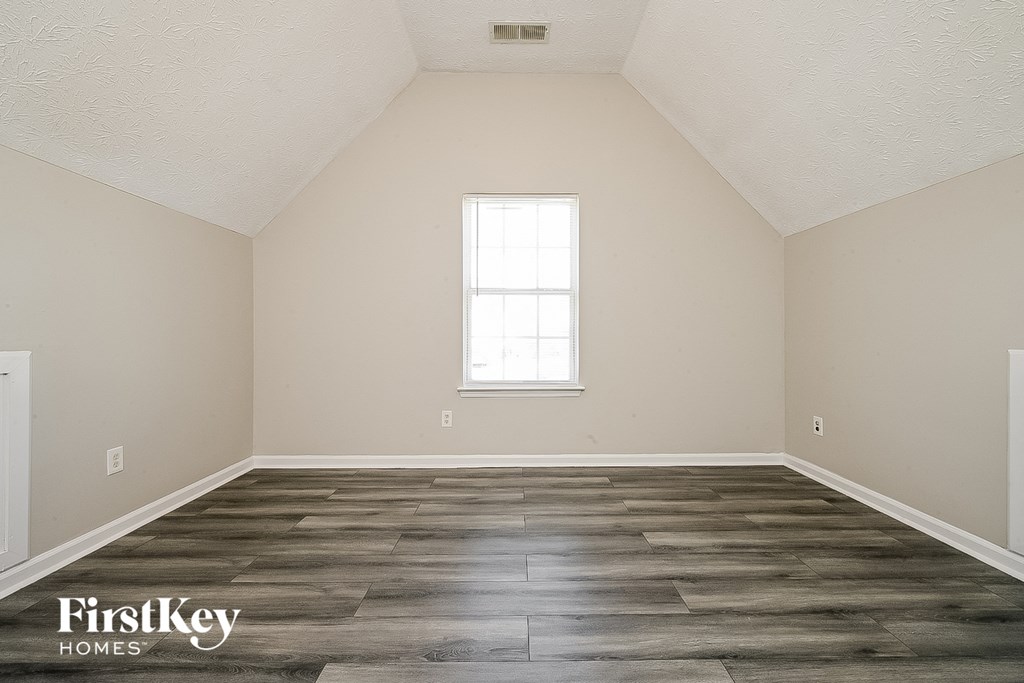 the living room of a home with wood floors and a window
