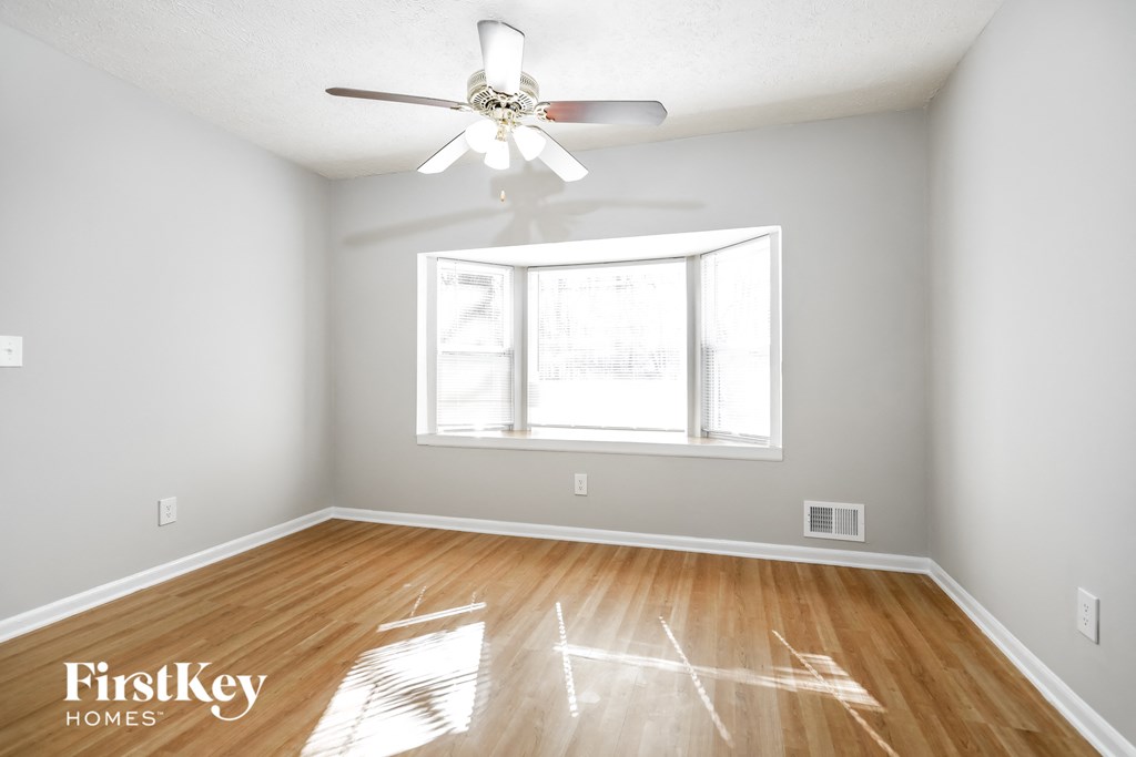 a bedroom with hardwood flooring and a window and a ceiling fan