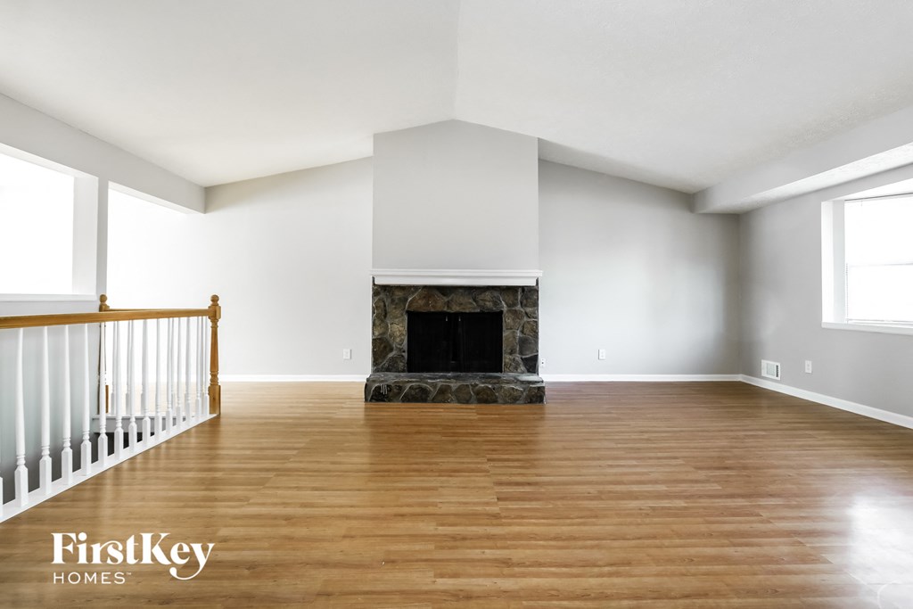 an empty living room with a fireplace and wooden floors