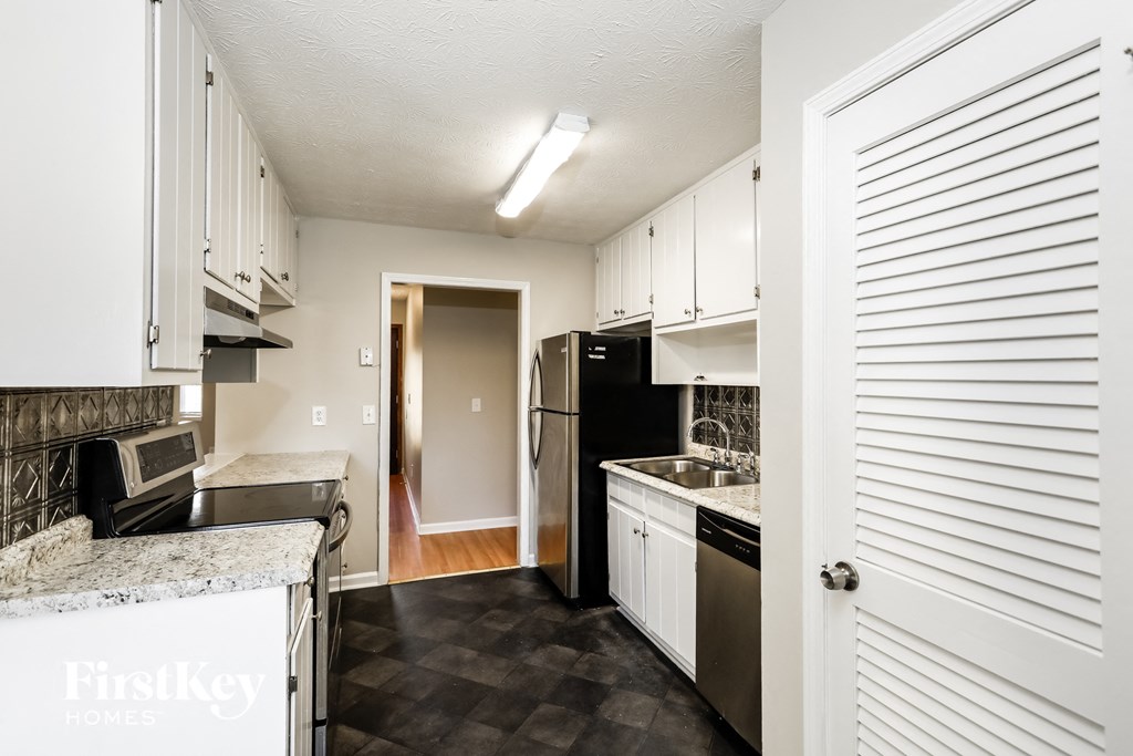 a small kitchen with white cabinets and black appliances
