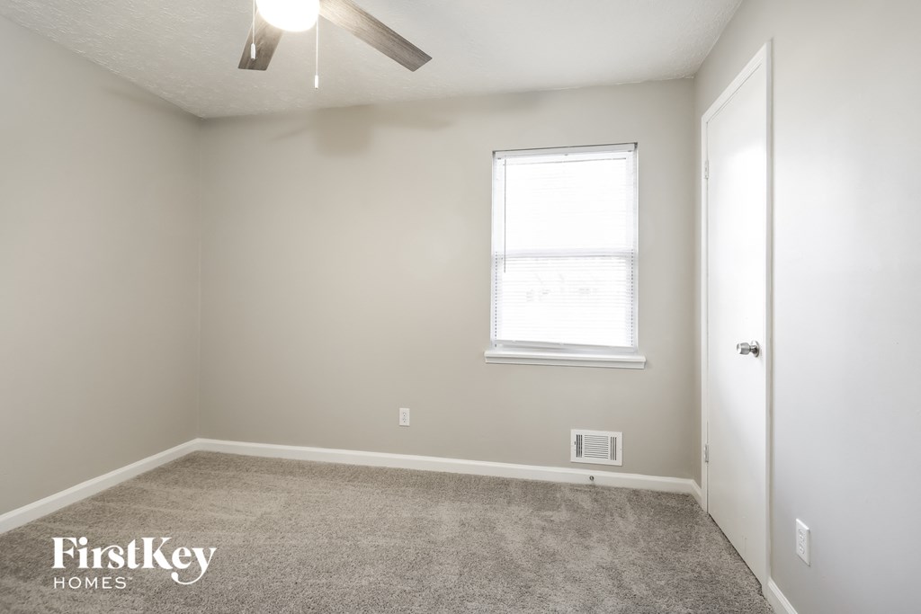 a carpeted room with a ceiling fan and a window