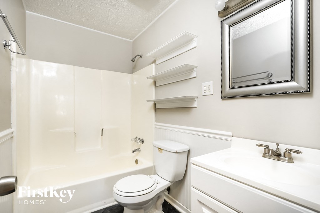 a bathroom with a toilet sink and tub and a mirror