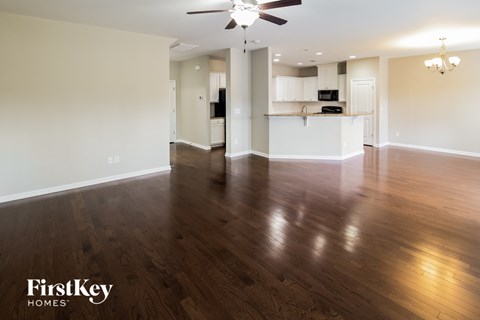 A spacious room with wooden floors and a ceiling fan.