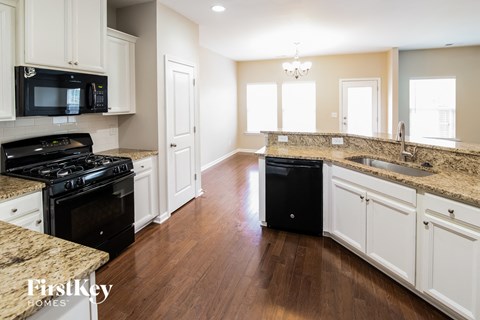 A kitchen with a black stove top oven and a black trash can.